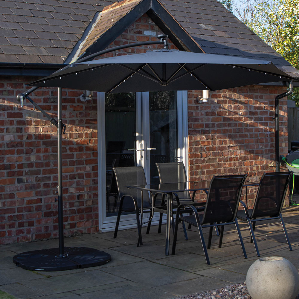Samuel Alexander 4 Seater Glass Top Outdoor Dining Set with Blue Banana Lit Parasol and Base Image 1